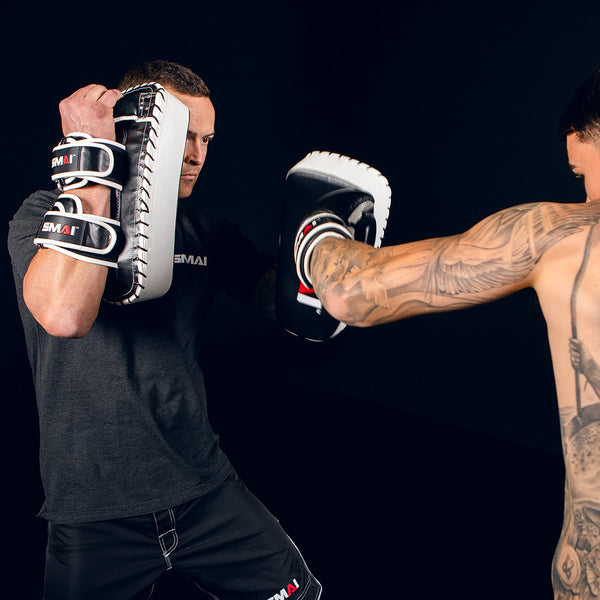 Man Holding Muay Thai Pads while man punches