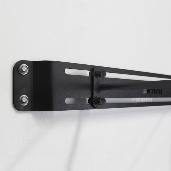 Close-up of the SMAI USA Workout Mat Wall Storage Rack, a black metal bracket with a laser-cut design, secured by two screws on a white wall—showcasing its sturdy, minimalist build for organizing workout mats.