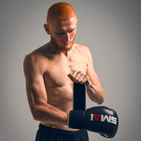 Man putting on the SMAI Essentials Boxing Glove